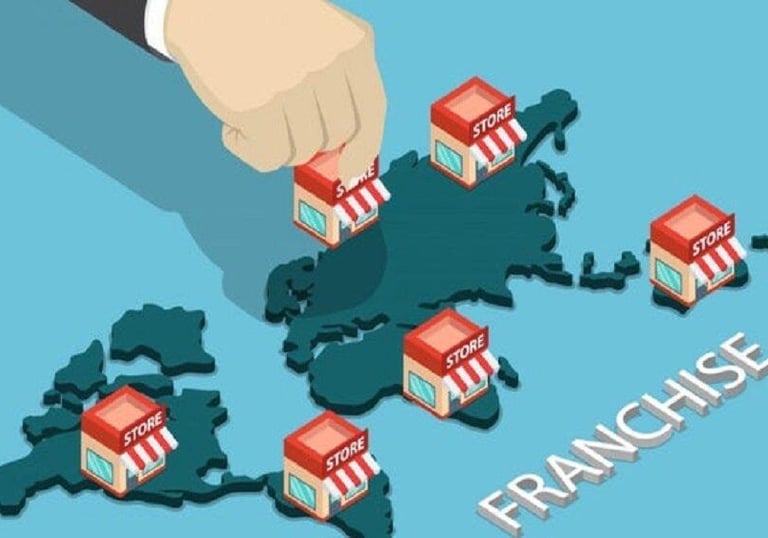 Isometric illustration of a hand placing franchise store buildings on a world map for global business expansion.