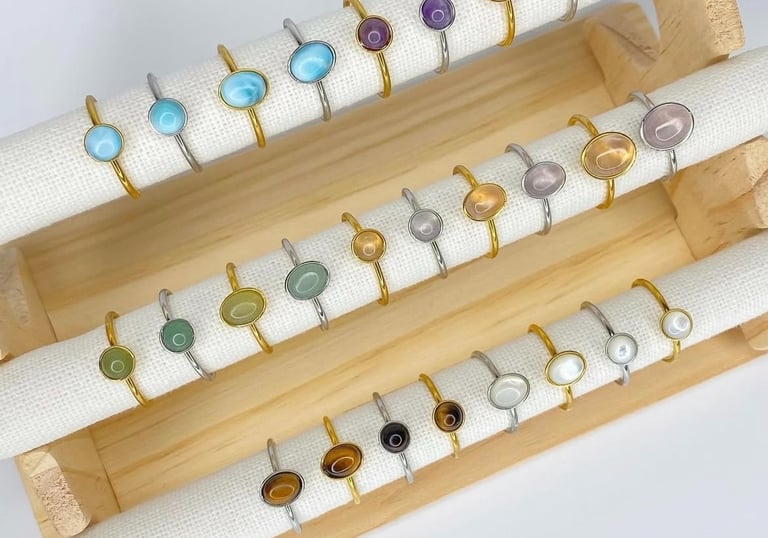 Anillos de piedras preciosas hechos a mano con bandas de oro y plata exhibidos en un soporte.