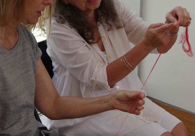 Instructor showing a student how to spin yarn