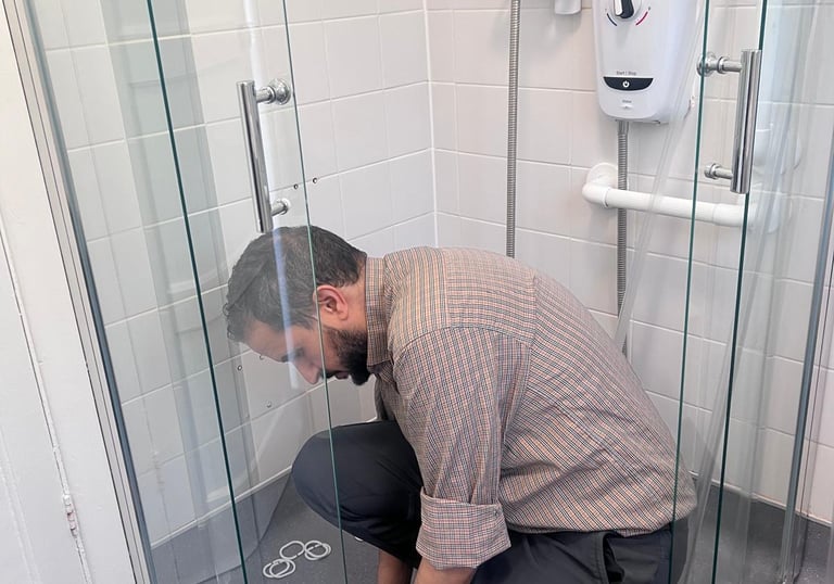 a man kneeling down on the ground repairing a shower