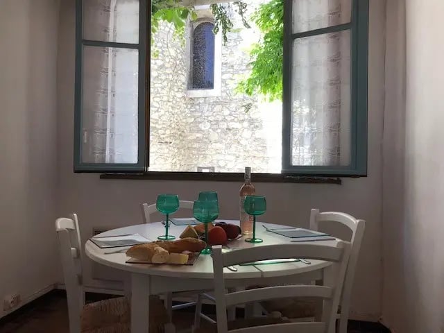 Dining area of holiday home in Quillan with open windows and church view