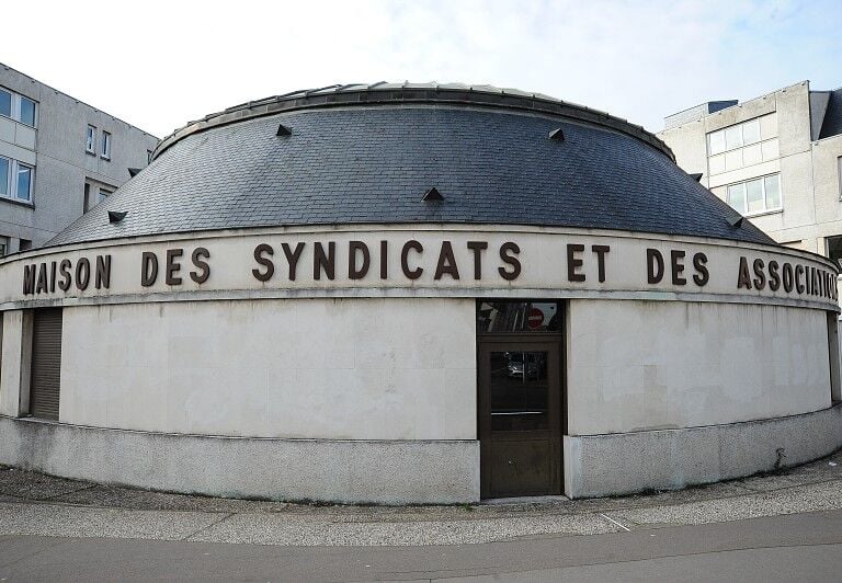 Photo de la Maison des Syndicats entourée de bâtiments, avec un bâtiment rond surnommé la Petite Rotonde