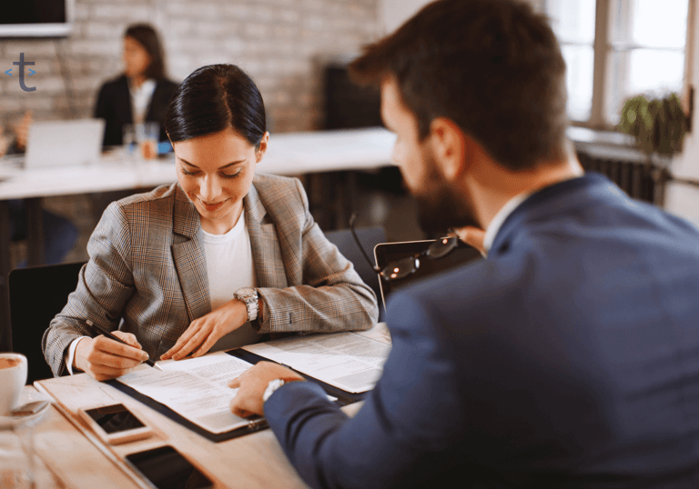 a man and woman sitting at a table with papers handling the EoR benefits administration