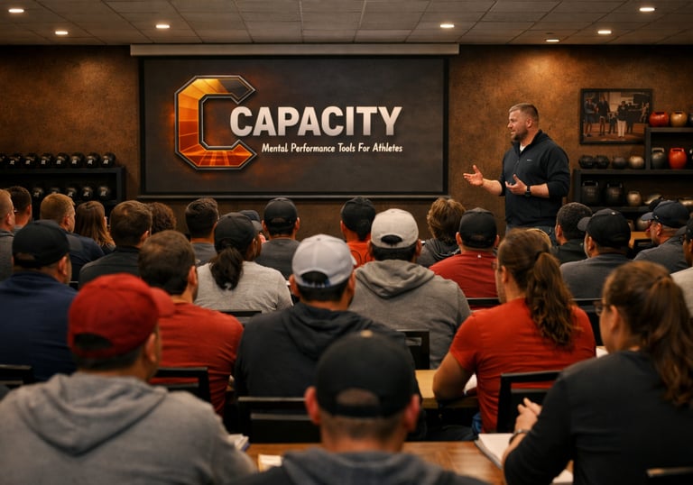 A speaker presenting Capacity mental performance tools for athletes to a large seated audience.