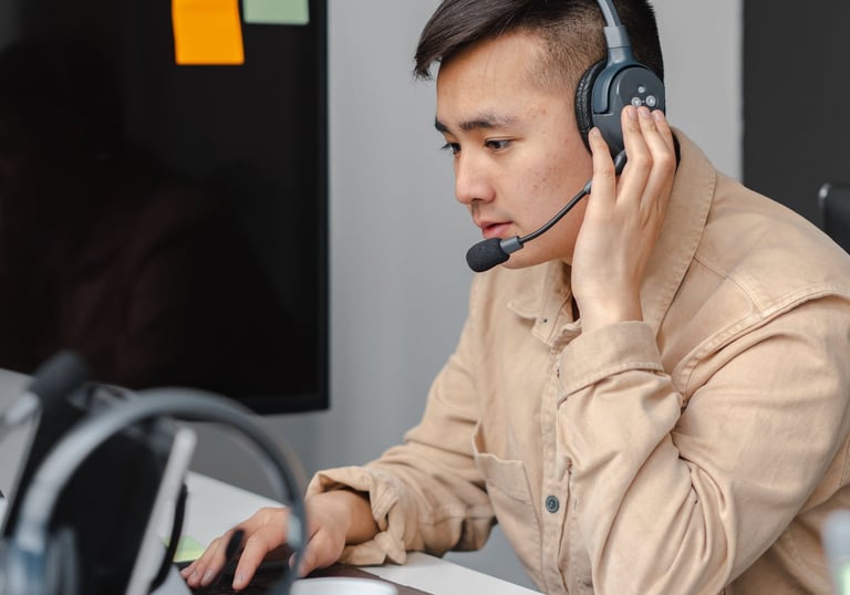 a man in a tan jacket and headphones on a laptop