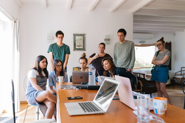 A team gathered around a laptop on a table, attending a virtual meeting.