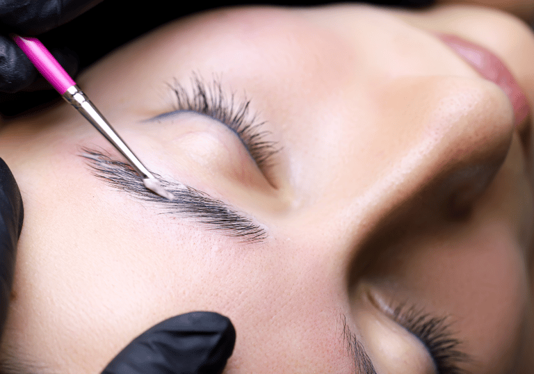 a woman getting her eyebrows laminated by a professional brow artist