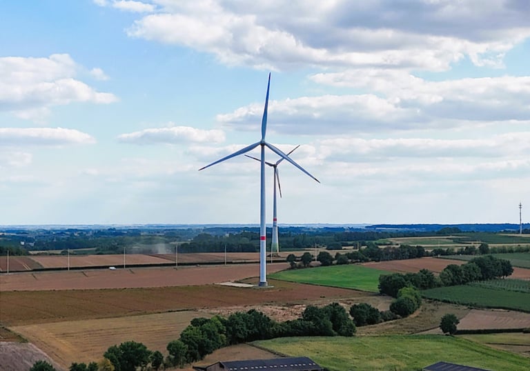Landschap met een windturbine in Zichem, omgeven door landbouwvelden en bomen onder een deels bewolkte heme
