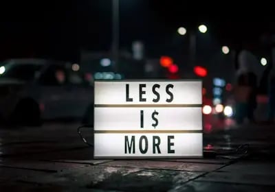 Lightbox with “Less is More” sign on a city street, symbolizing Binance’s low trading fees and extra