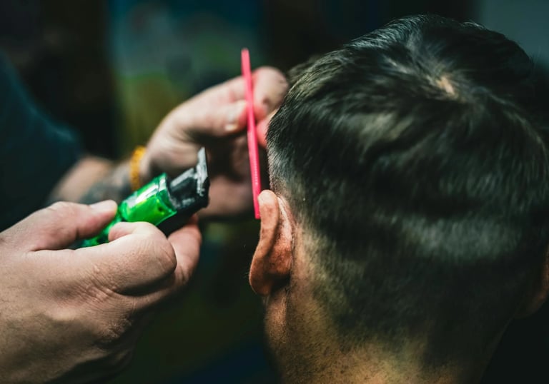 a man is shaving a man's hair while he is getting his hair