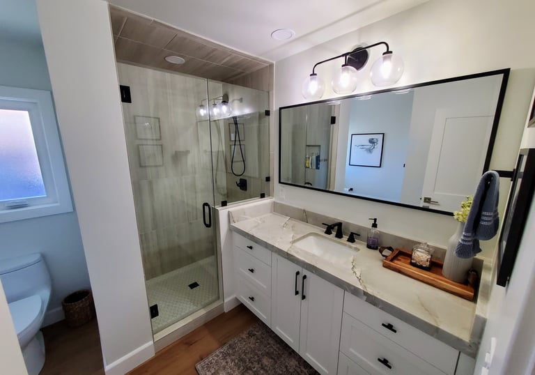 Renovated bathroom with large mirror and black hardware. Colorado Springs bathroom remodel.