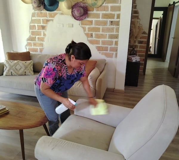 a woman cleaning a couch with a sponge pad