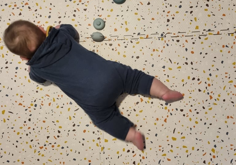 a baby is laying on a floor with a teddy bear