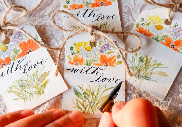 NYC calligrapher writing the words “with love” for a gift tag with handmade watercolor florals
