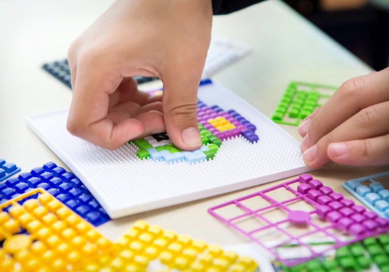 A child creates a picture using colored silicone pixel squares on the baseplate