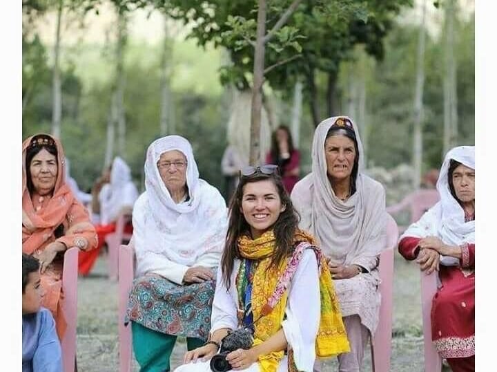Eva zu Beck stands with local Hunza women, all in vibrant traditional attire and signature caps, sha