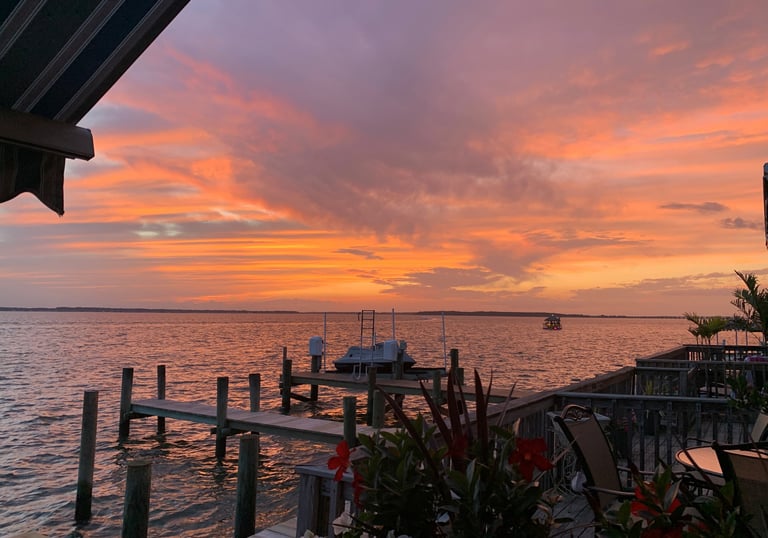 a sunset view of a dock with chairs and tables