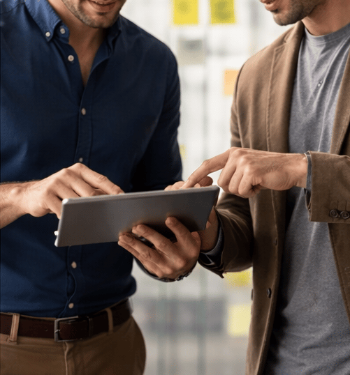 Dos profesionales analizando información en una tablet en reunión estratégica.