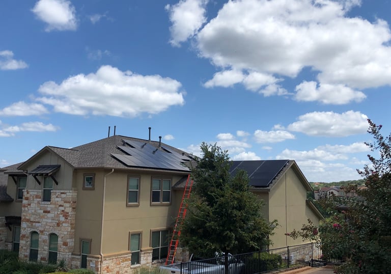 Professional residential solar panel installation on a modern home roof with an orange ladder.