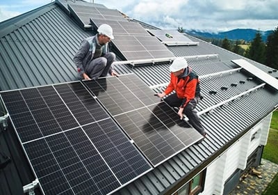 Professional technicians installing solar panels on a residential metal roof for renewable energy.