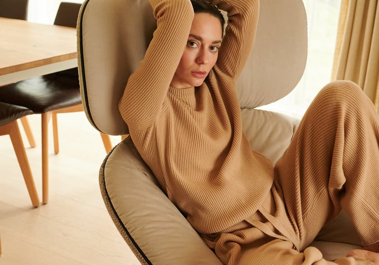 a woman sitting on a chair with her hands on her head