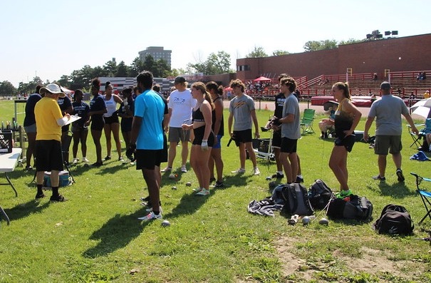 Group of track and field athletes gathered outdoors during a ThrowersClub meet, preparing for events