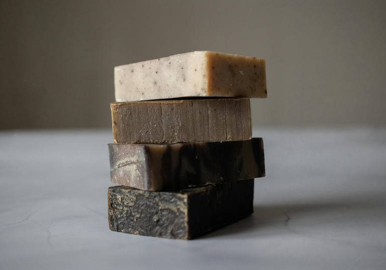 Stack of handcrafted goat milk soap bars in various natural colors, made with organic ingredients