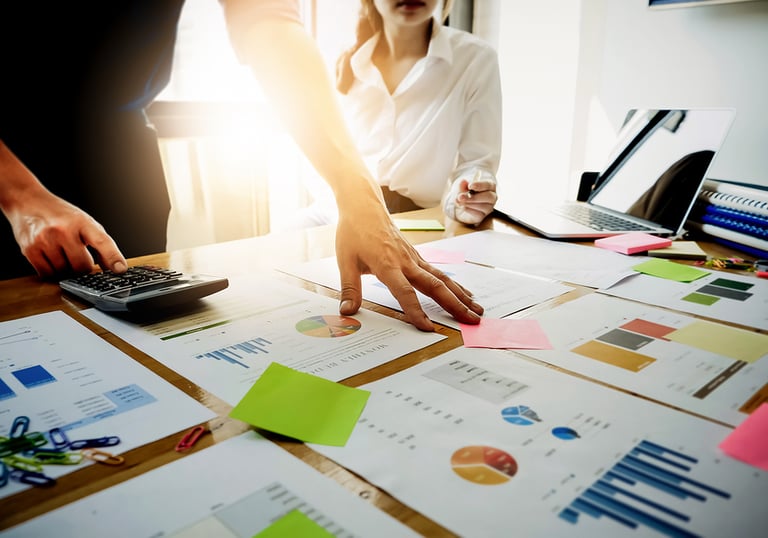 Two business professionals analyzing financial charts and data on a desk.