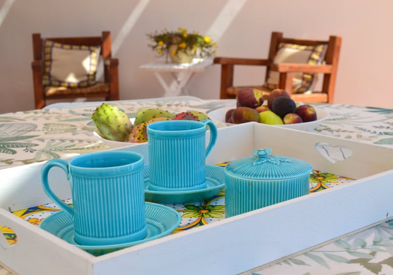 a tray with a tray of tea cups and a bowl of fruit