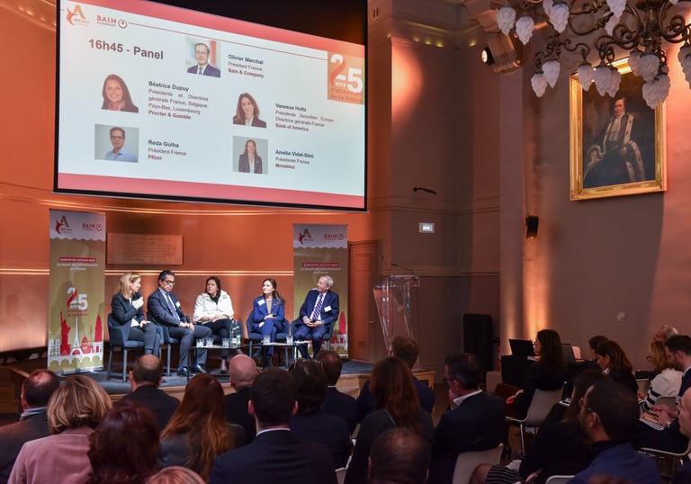 5 dirigeants d'entreprises sont sur scène lors d'une conférence, face à un public dans la pénombre.