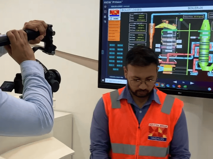 a man in a blue shirt and a camera shooting video of another man looking down