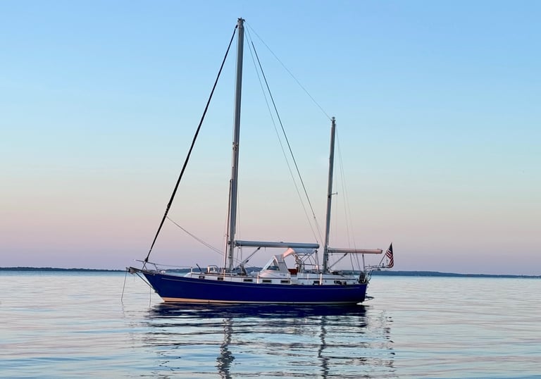 Sailboat anchored at sunset with no sails up while passenger enjoy a charter on buzzards bay