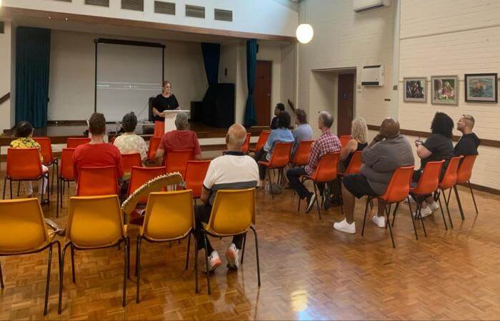 a person standing in front of a room filled with people listening