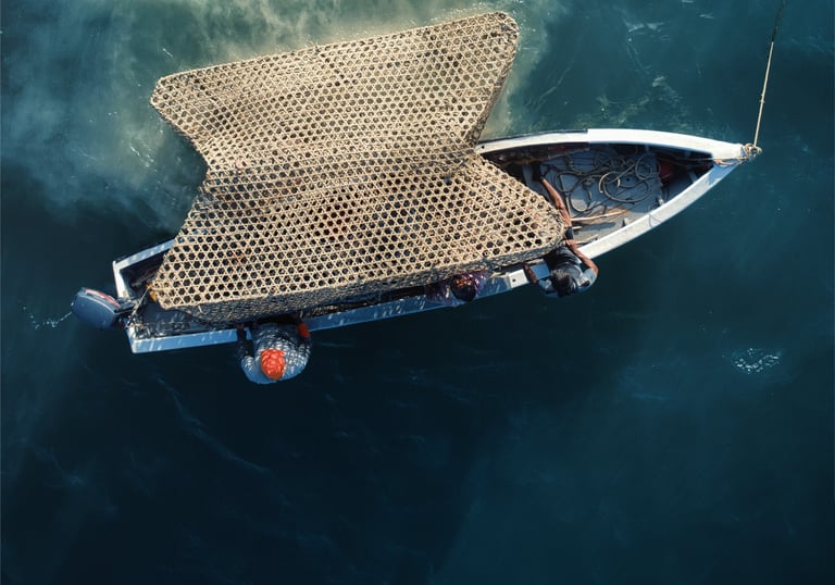 Aerial view of a fishing boat at sea carrying large, stacked bamboo traps on deep blue water.