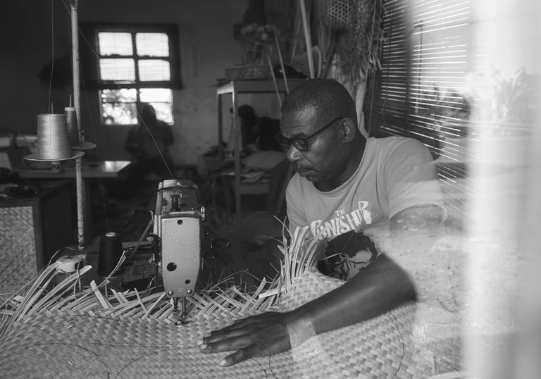 A man in Rodrigues sewing traditional woven material using a machine inside a workshop