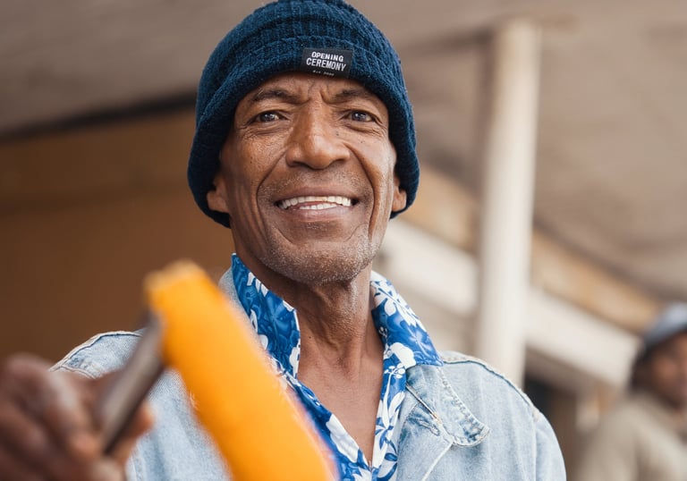 Man in a beanie hat smiling while holding roasted corn in Rodrigues.