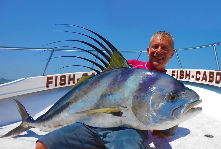 an angler holding a huge Roosterfish hooked close to a San Jose del Cabo's beach