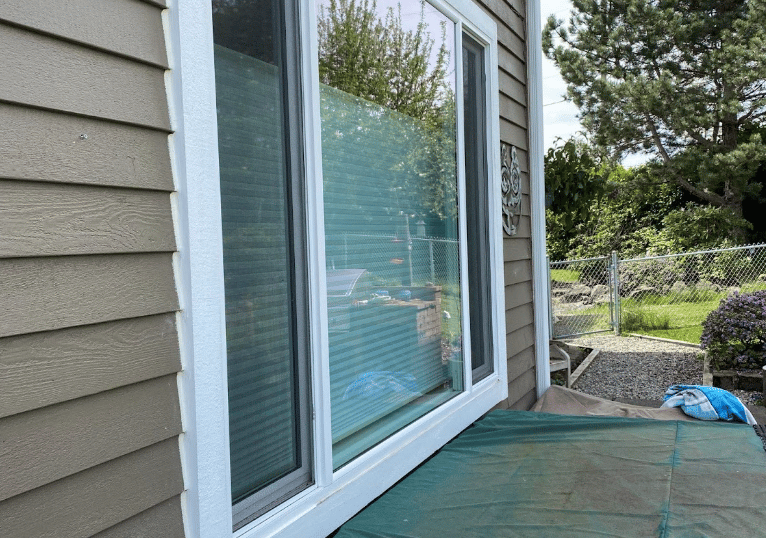 Exterior view of a house showing large sliding glass doors and siding.