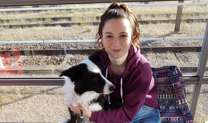 a woman in a purple jacket is holding a dog