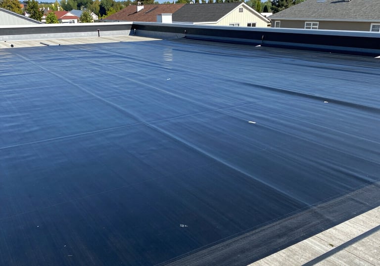 A person wearing safety gear is suspended by ropes, performing maintenance or cleaning on the side of a large building with vertical panels.