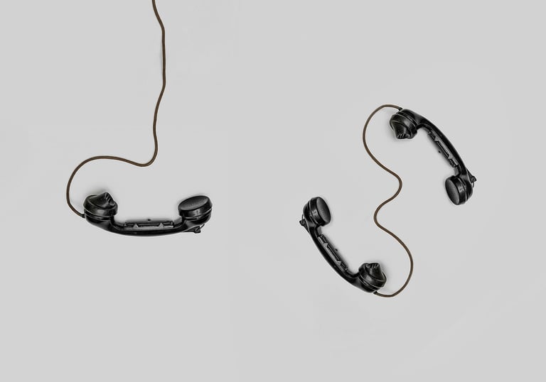 A beige solid background with three wired old fashioned phones places at different angles