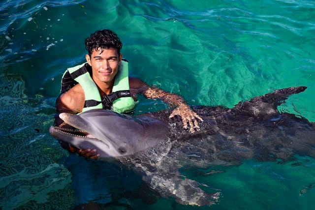 a man in a life jacket is holding a dolphin dolphines punta cana