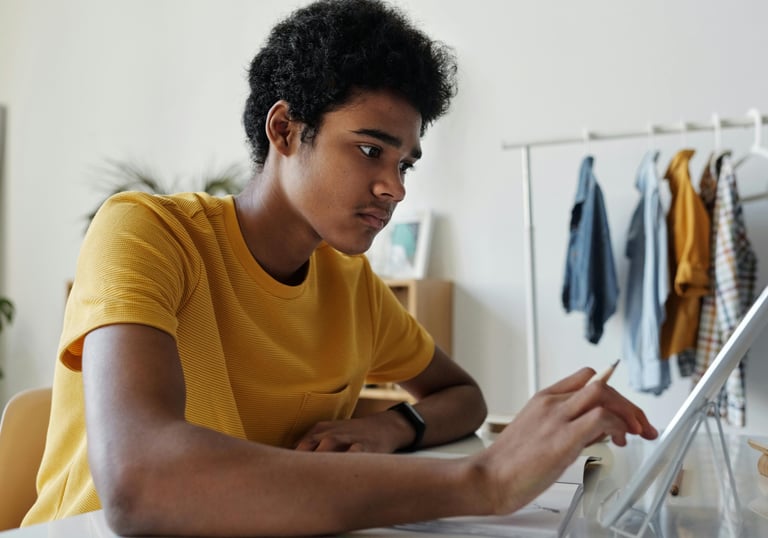 a student sitting at a table with a laptop computer during online tuition