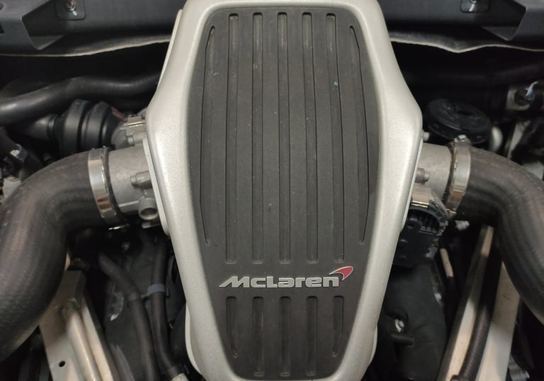 an Enlab close up of a McLaren sports car engine with a motorbike