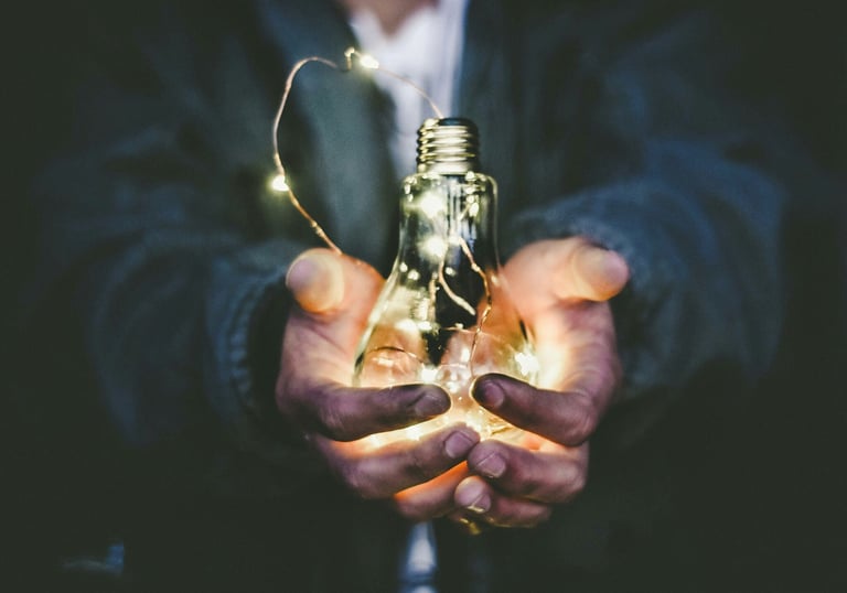 an older man holds a lightbulb, symbolizing the knowledge and mentorship he is providing