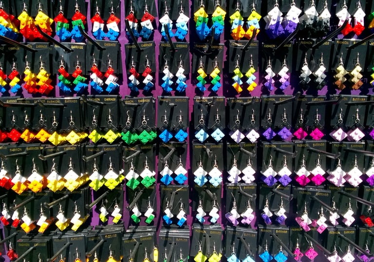 A vibrant display of handmade colorful LEGO earrings hanging on black retail display cards.