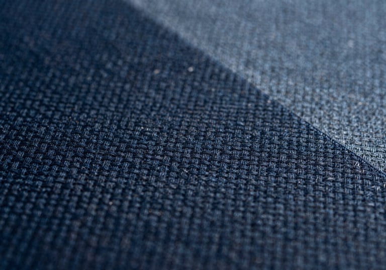 Macro shot of athletic textile fabric texture, showing precision weaving in dark navy and slate blue.