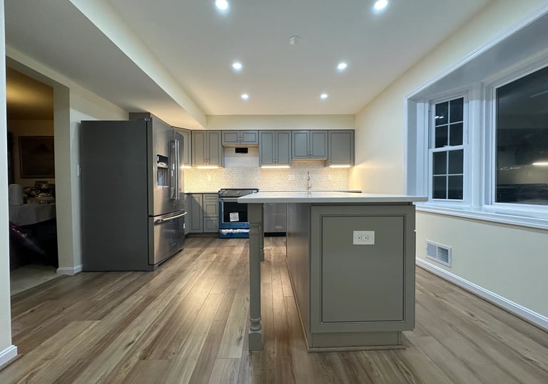 Grey shaker cabinets, stainless steel appliances, and quartz counters in a new kitchen.