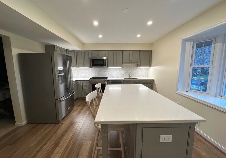 Grey kitchen remodel with quartz counters, stainless steel sink, and brown LVP flooring.