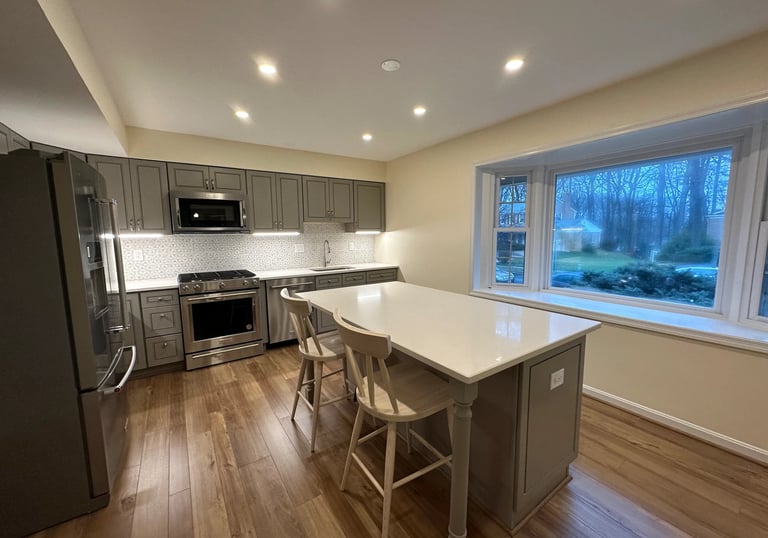 A beautifully updated kitchen featuring gray shaker cabinets, quartz countertops, and warm LVP